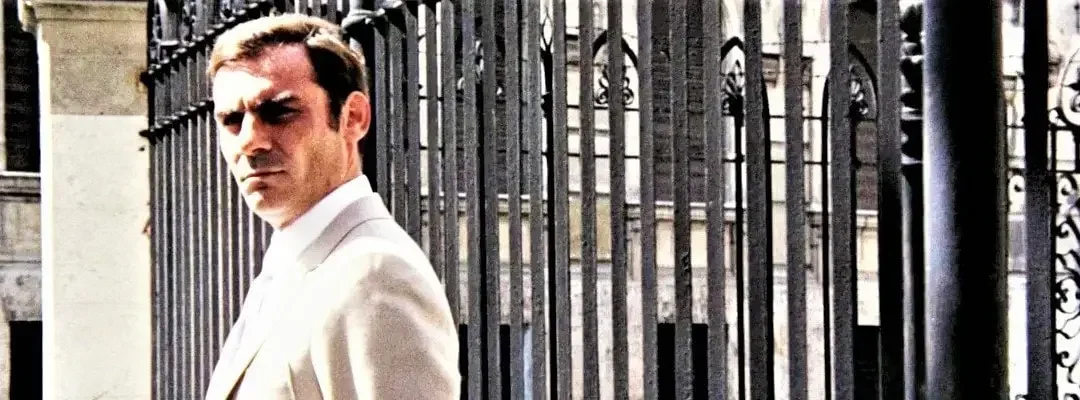 Gianmaria Volontè in una scena di Indagine su un cittadino al di sopra di ogni sospetto ripreso davanti ad un grande cancellata